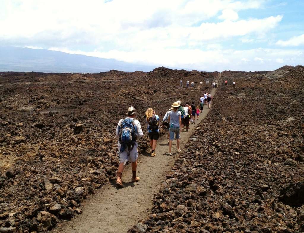 Group of hikers walk along a straightened path in lava field