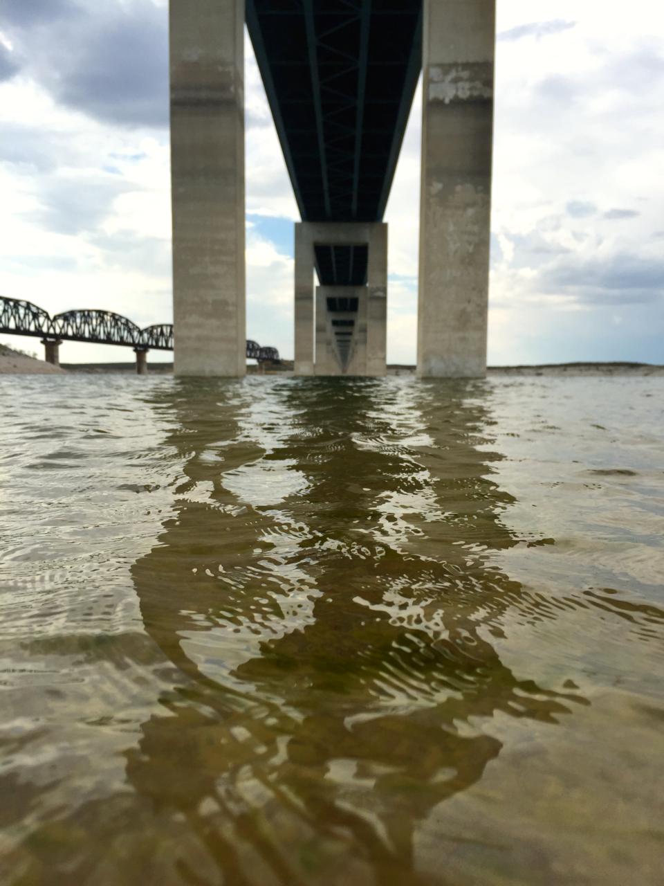 Taken from a boat on the water, the image shows the underbelly of a bridge and the supports.