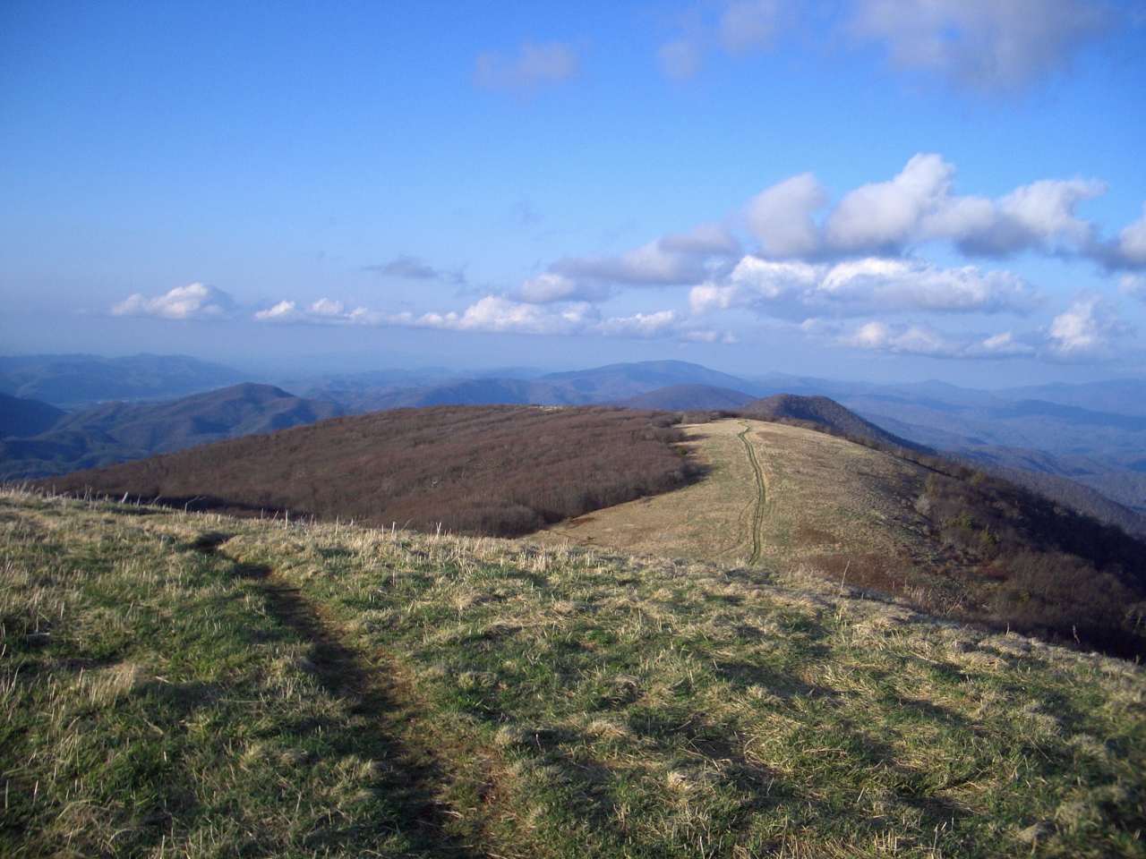 The Appalachian Trail runs across a mountain ridge line with views to the horizon of mountain range.