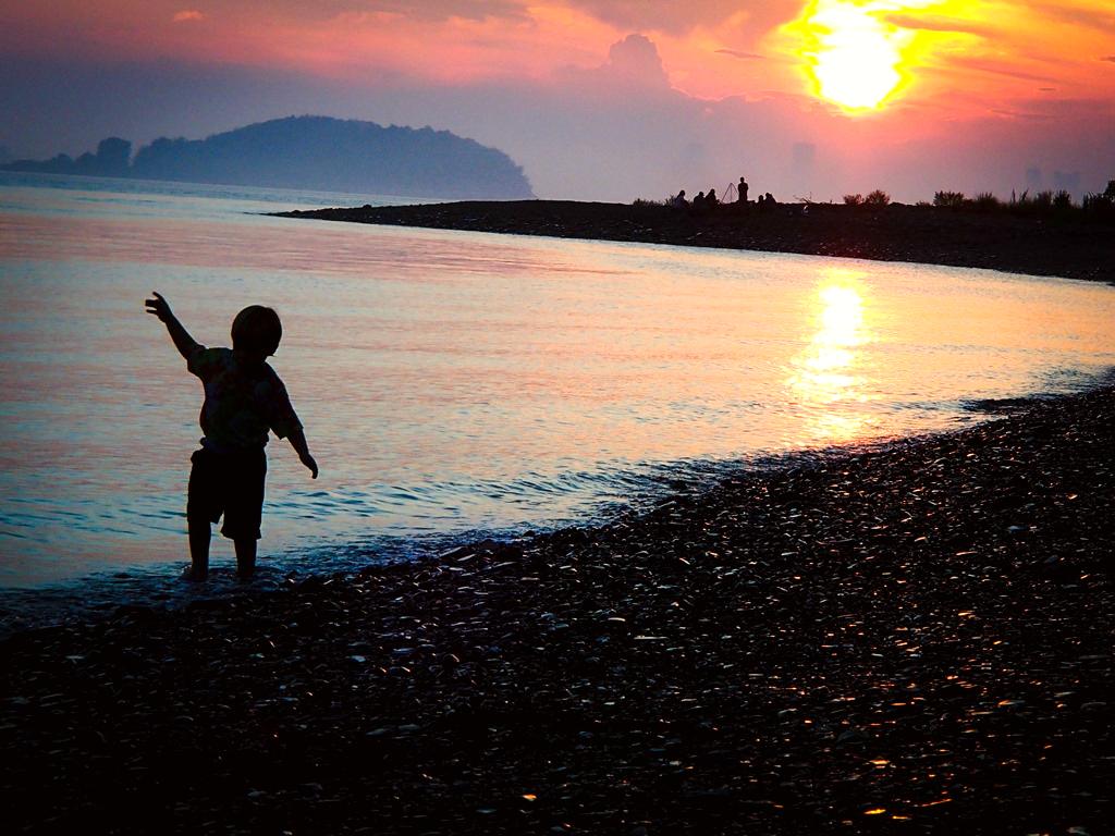 A child dancing on the beach at dusk