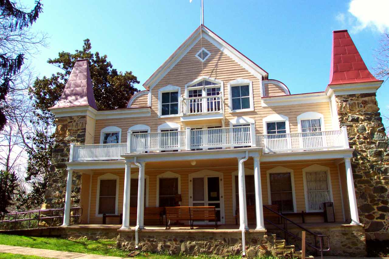 two and half story wooden frame house with double porch and stone corner posts.