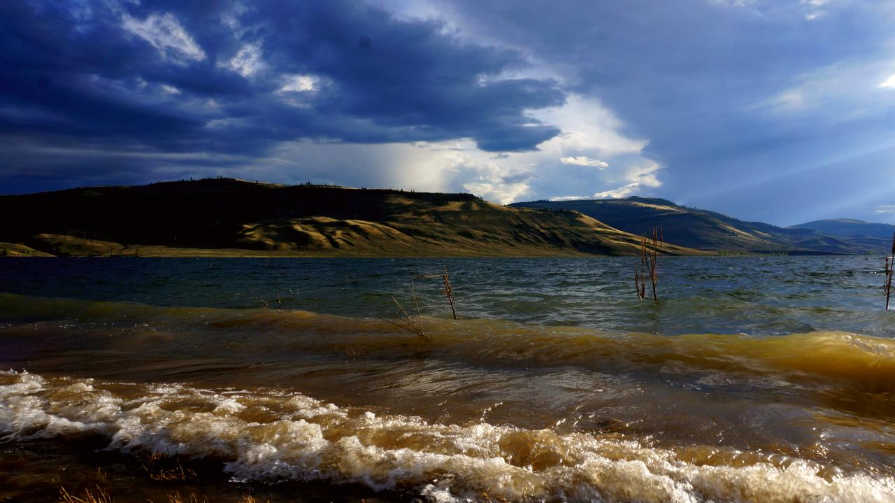 Underexposed shot of waves coming off a reservoir. Mesas in the background.