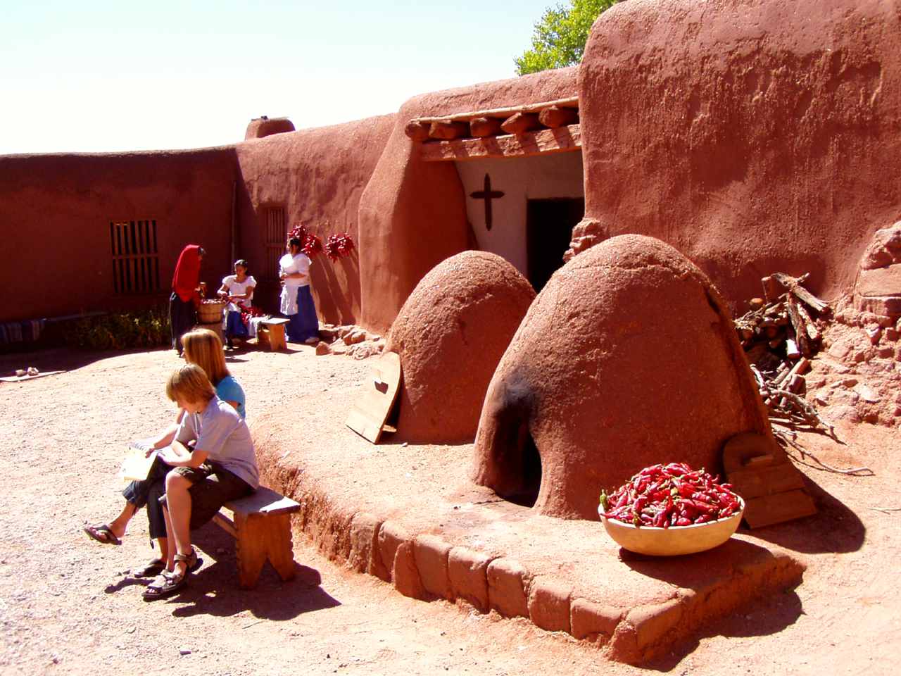 adobe buildings including two beehive-looking ovens with people in a courtyard