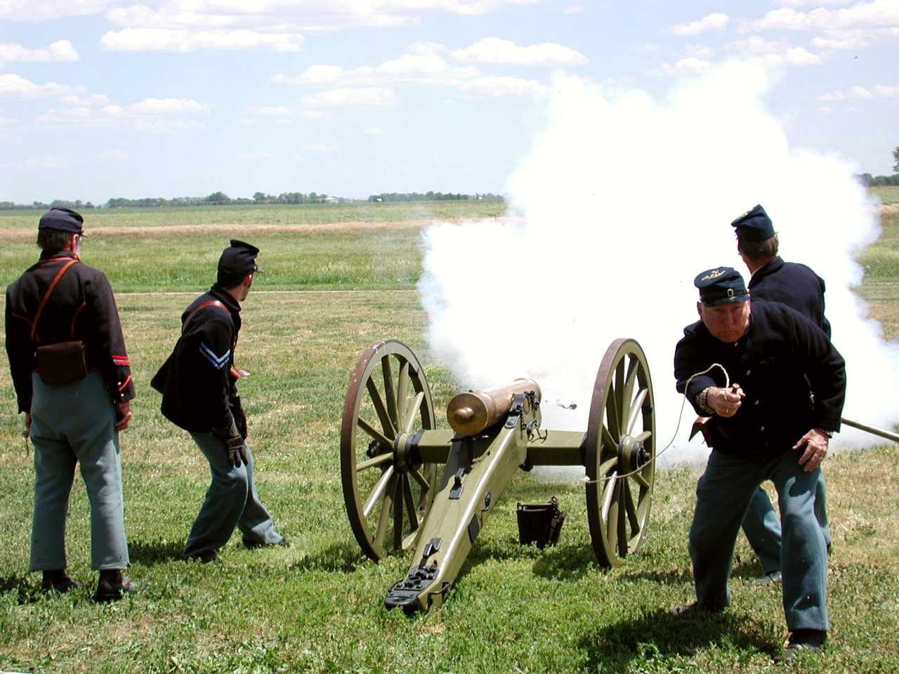 Men in 19th century U.S. Army uniforms fire a reproduction period cannon.