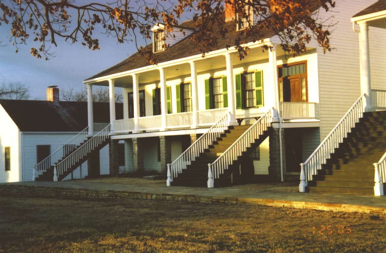 Wood frame structures with stairs next to a stone walkway. Structures reflect afternoon sunlight.