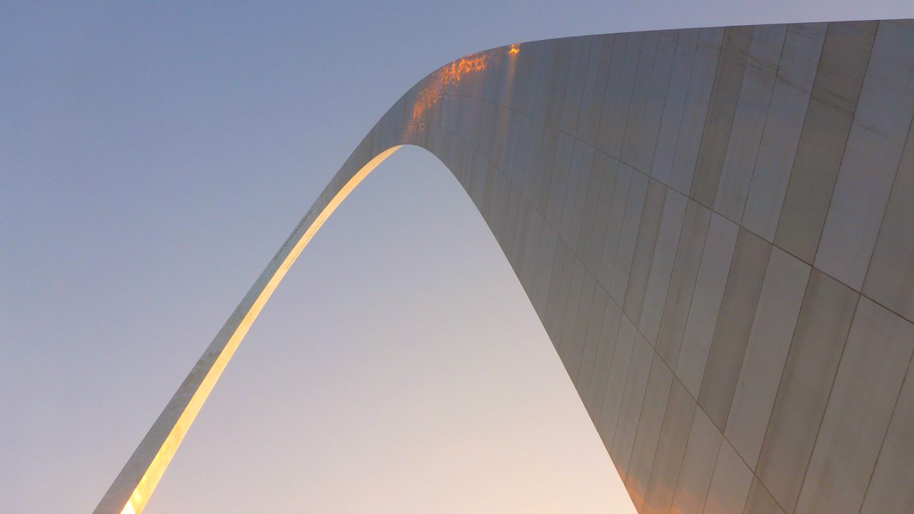 looking up at the curve of the Gateway Arch against the sky