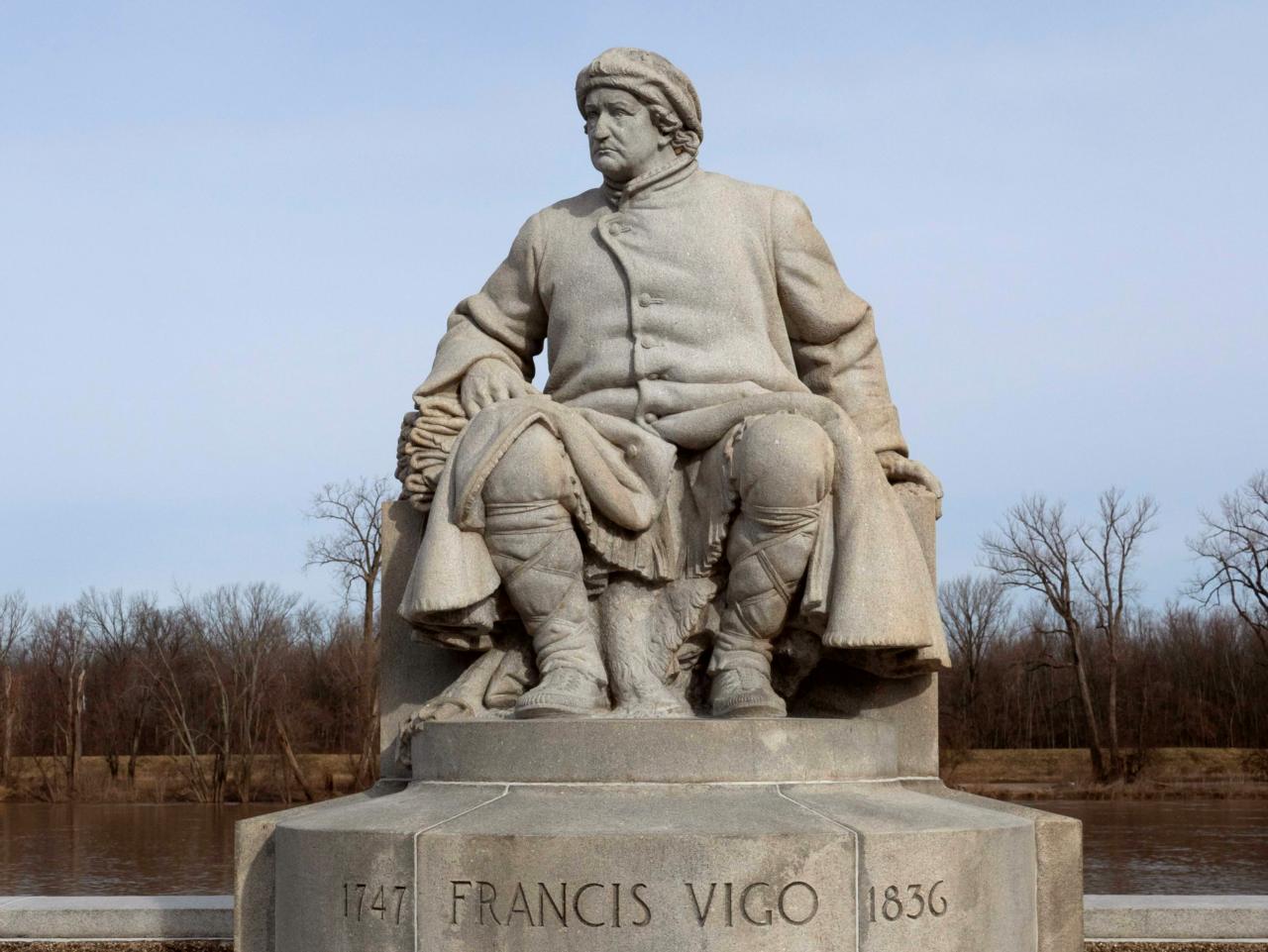 A granite statue of Francis Vigo, seated, dressed in 18th century fur trader clothing