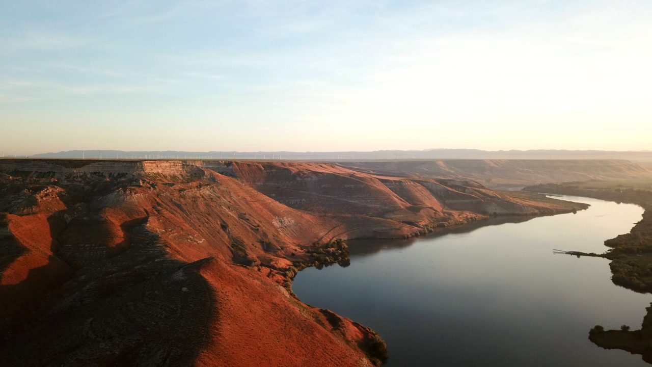 Steep, rocky bluffs line a river, awash in warm sunset colors