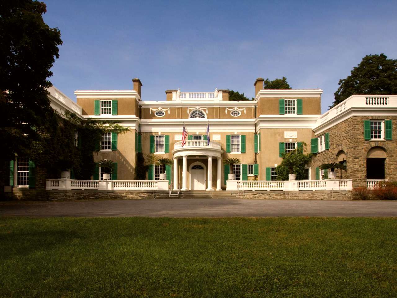 A stucco and fieldstone house with white trim and circular portico.