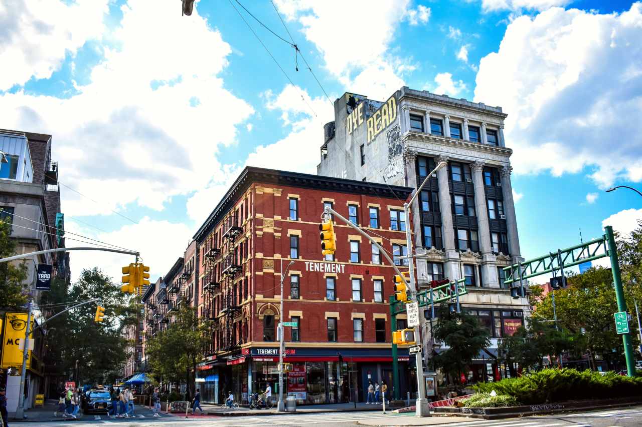 A four story red brick building against a blue sky with white puffy clouds