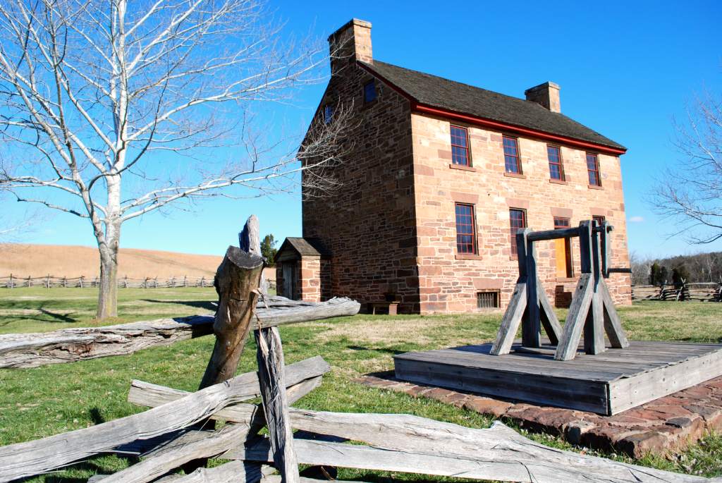 View of Stone House, with worm rail fence and well in front yard.