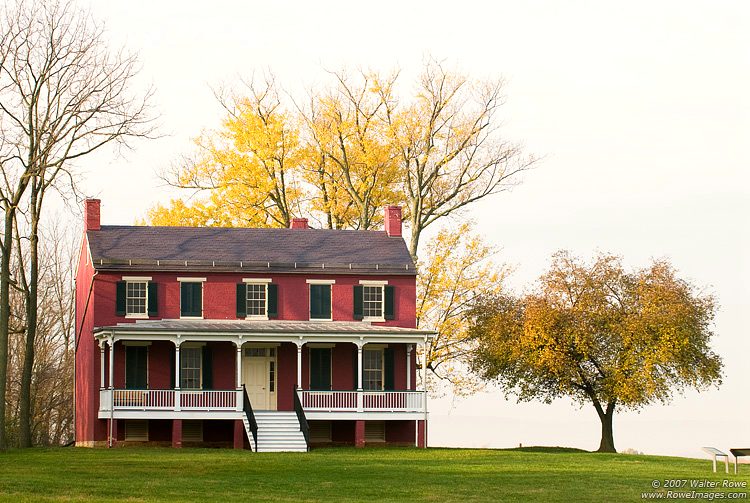 Federal style house with trees behind it during the fall season.