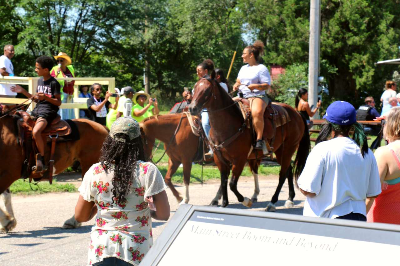 A group of people watching people on horseback during a parade