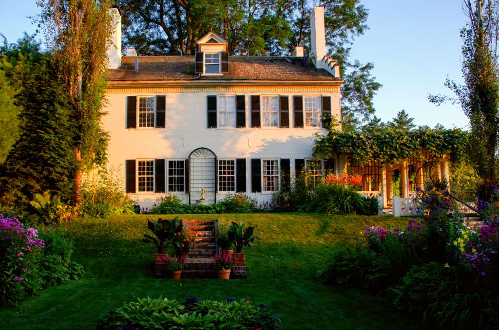 historic white brick house with flower gardens