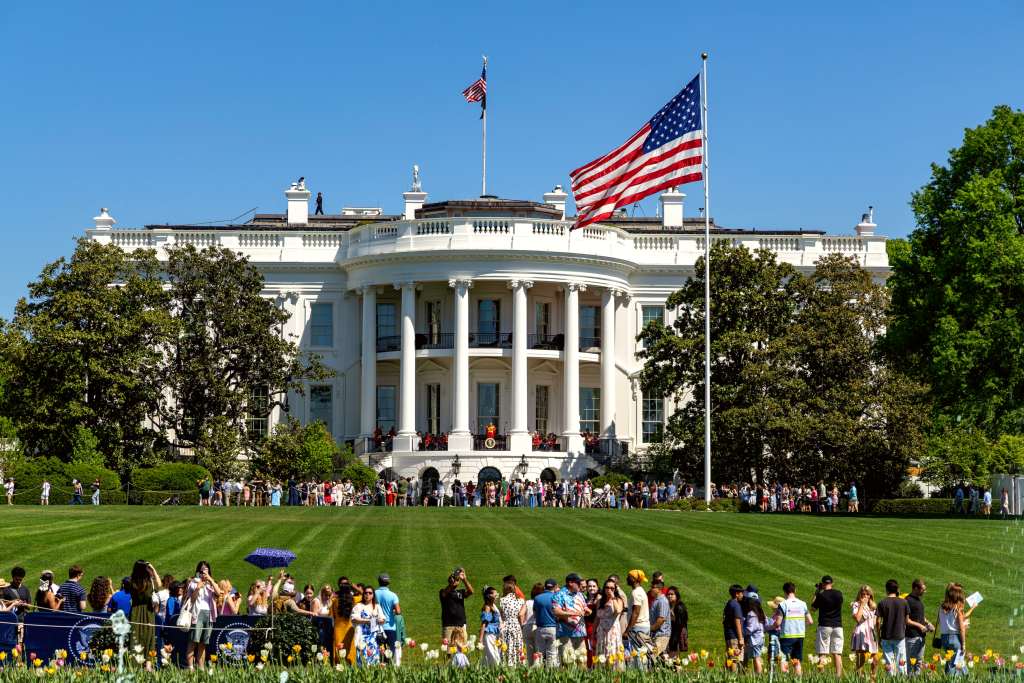 Crowds of people populate the White House South Lawn on a sunny day with the White House in view