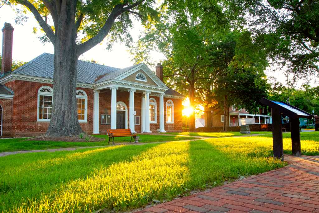 Historic Gloucester Courthouse with white columns at sunrise.
