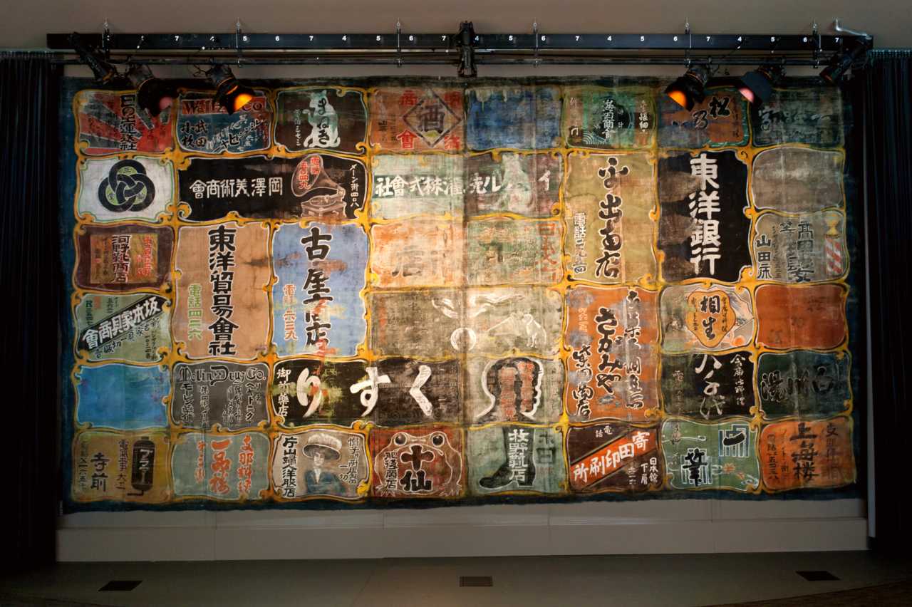 theatre curtain painted with Japanese characters advertising local businesses