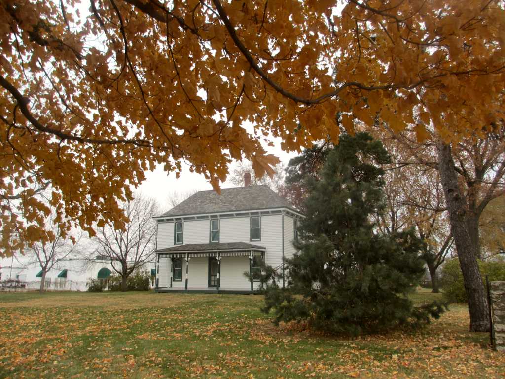 The Truman Farm Home sits behind Autumn trees.