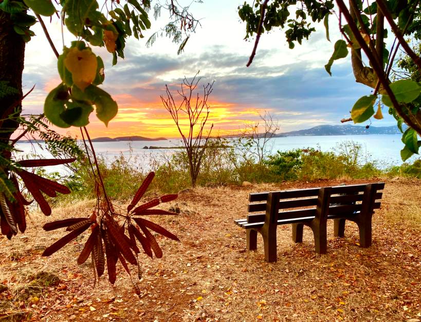 A sunset colors the horizon as seen from an overlook above the bay.