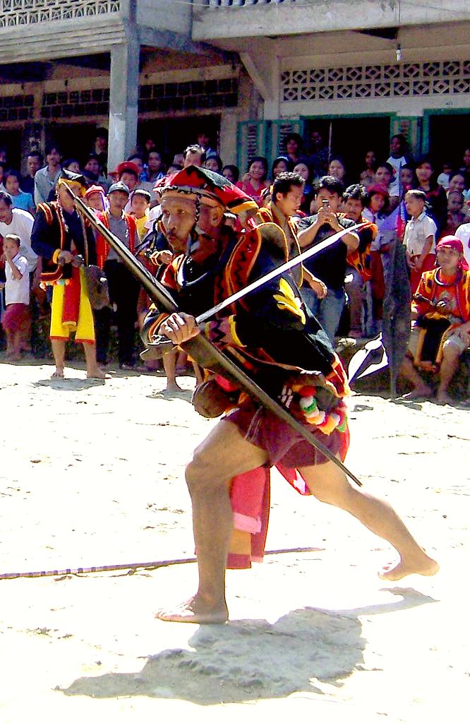 A man holding a Balato (sword) in a Nias war dance.