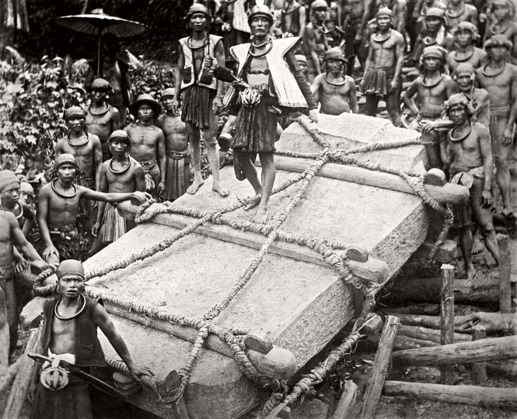 Nias men carrying a stone for construction for the deceased ruler Saunigeho of Bawömataluo around 1915.