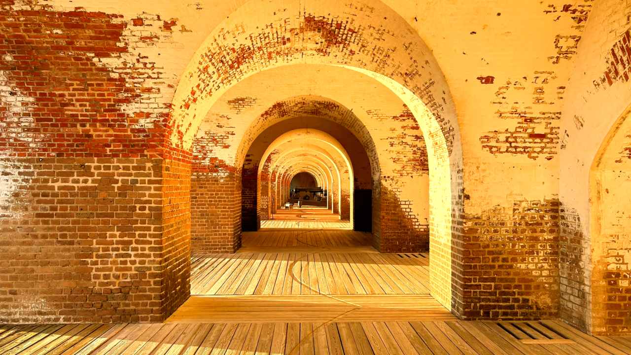 The brick of the fort glow in the late afternoon light. The arches inside the fort reveal a cannon i