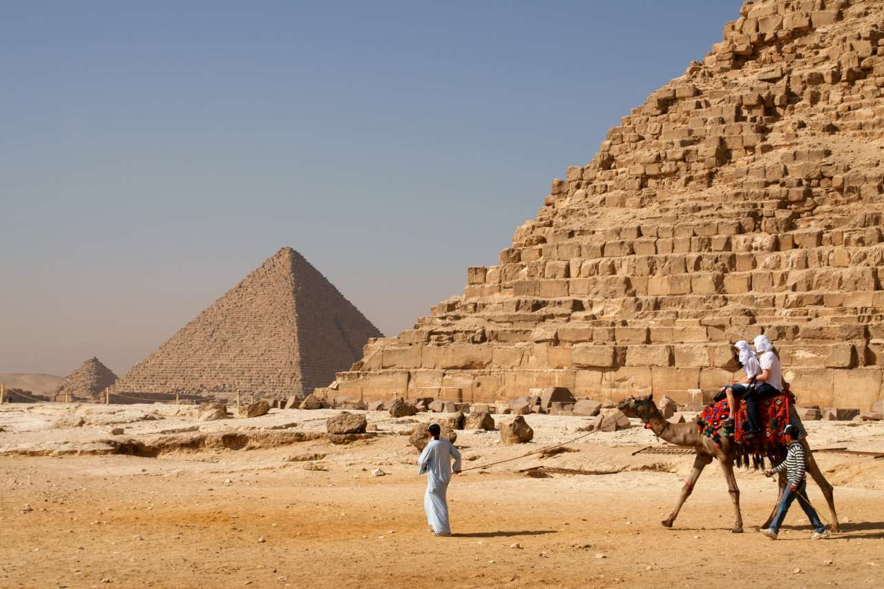 Tourists riding an Arabian camel in front of Pyramid of Khafre. The Giza Necropolis is one of Egypt's main tourist attractions.
