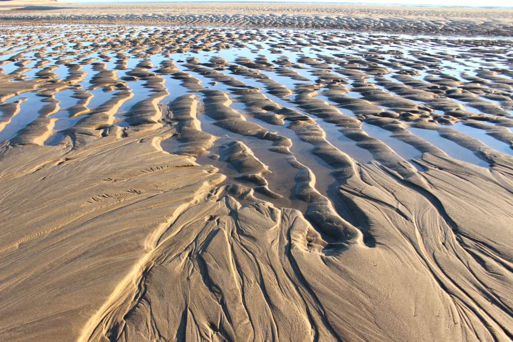 Low tide exposes rippled ridges of sand and water.