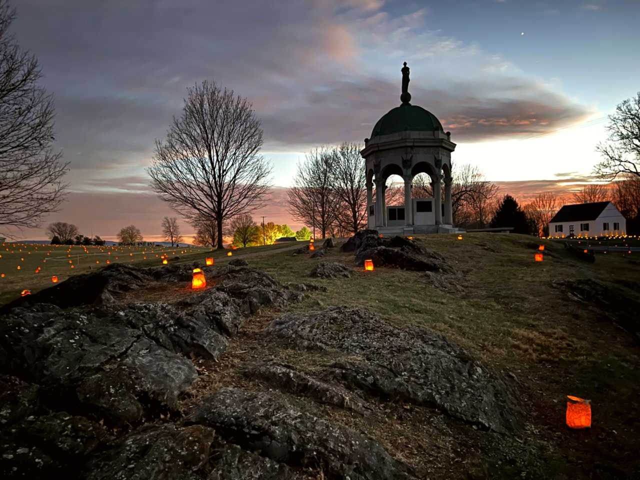 luminaries placed by Maryland Monument with dramatic orange red clouds